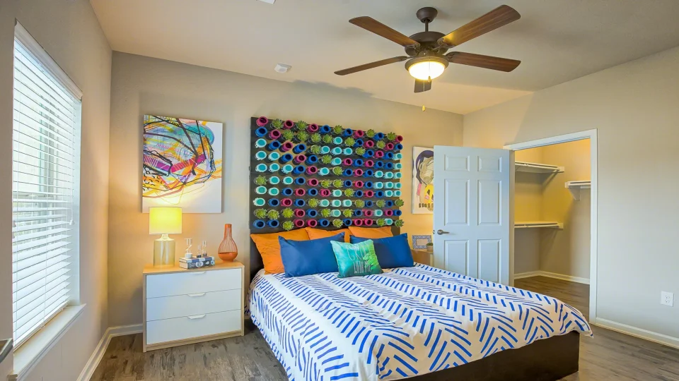 a bedroom with a colorful bedspread and a ceiling fan at The Creekside at Kenneys Fort